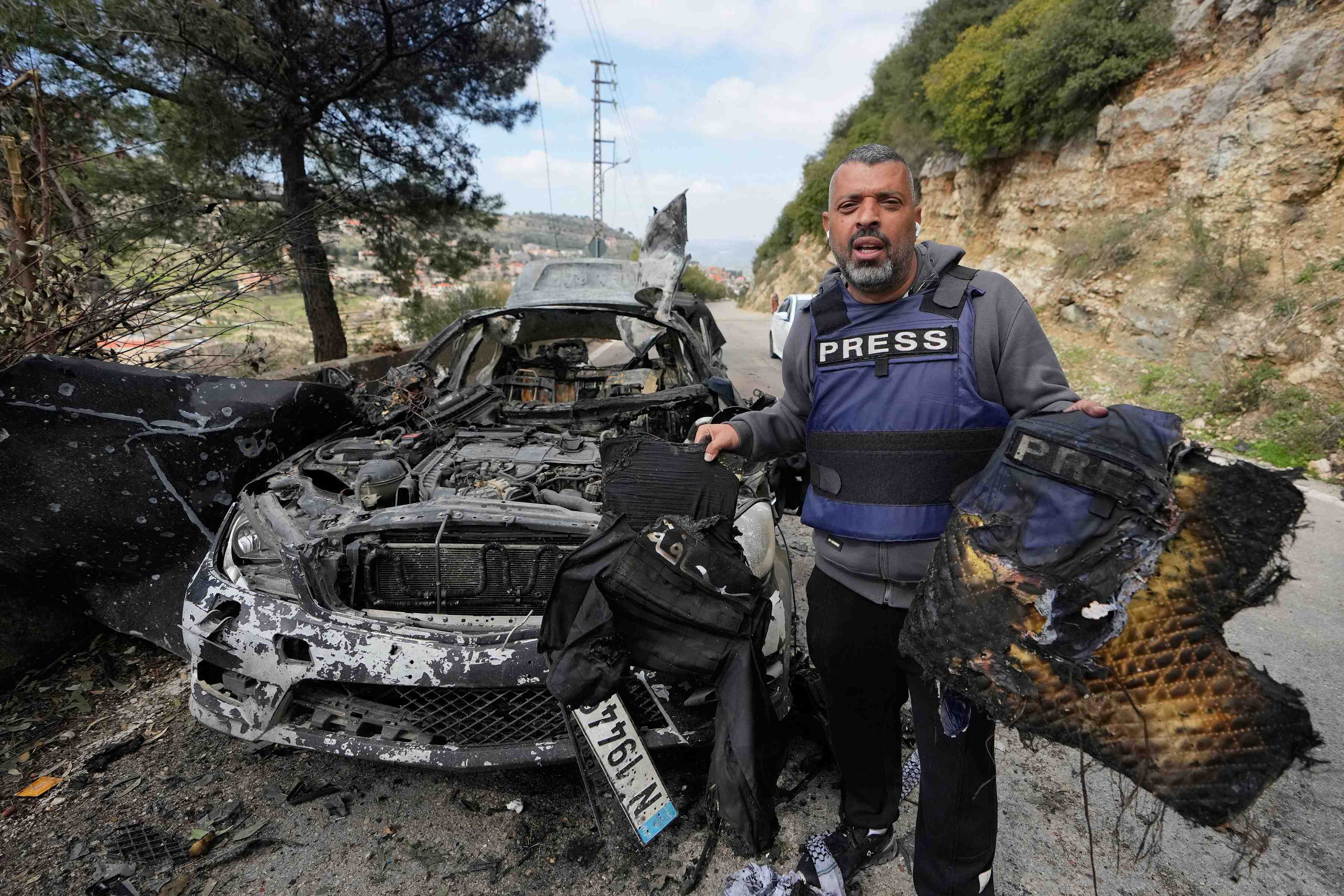 A journalist holds burnt safety equipment recovered from a vehicle struck in an Israeli airstrike that killed three journalists in southern Lebanon on March 28, 2026. (Image Credits: AP/Mohammed Zaatari)