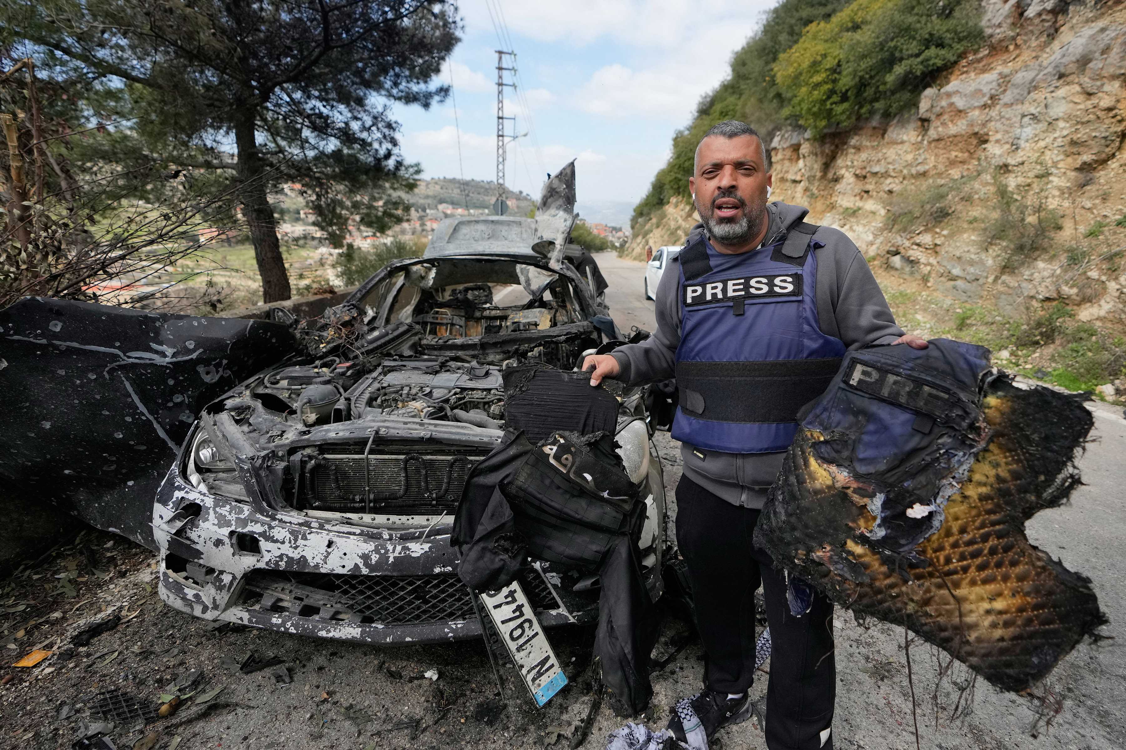 A journalist holds burnt safety equipment recovered from a vehicle struck in an Israeli airstrike that killed three journalists in southern Lebanon on March 28, 2026. (Image Credits: AP/Mohammed Zaatari)
