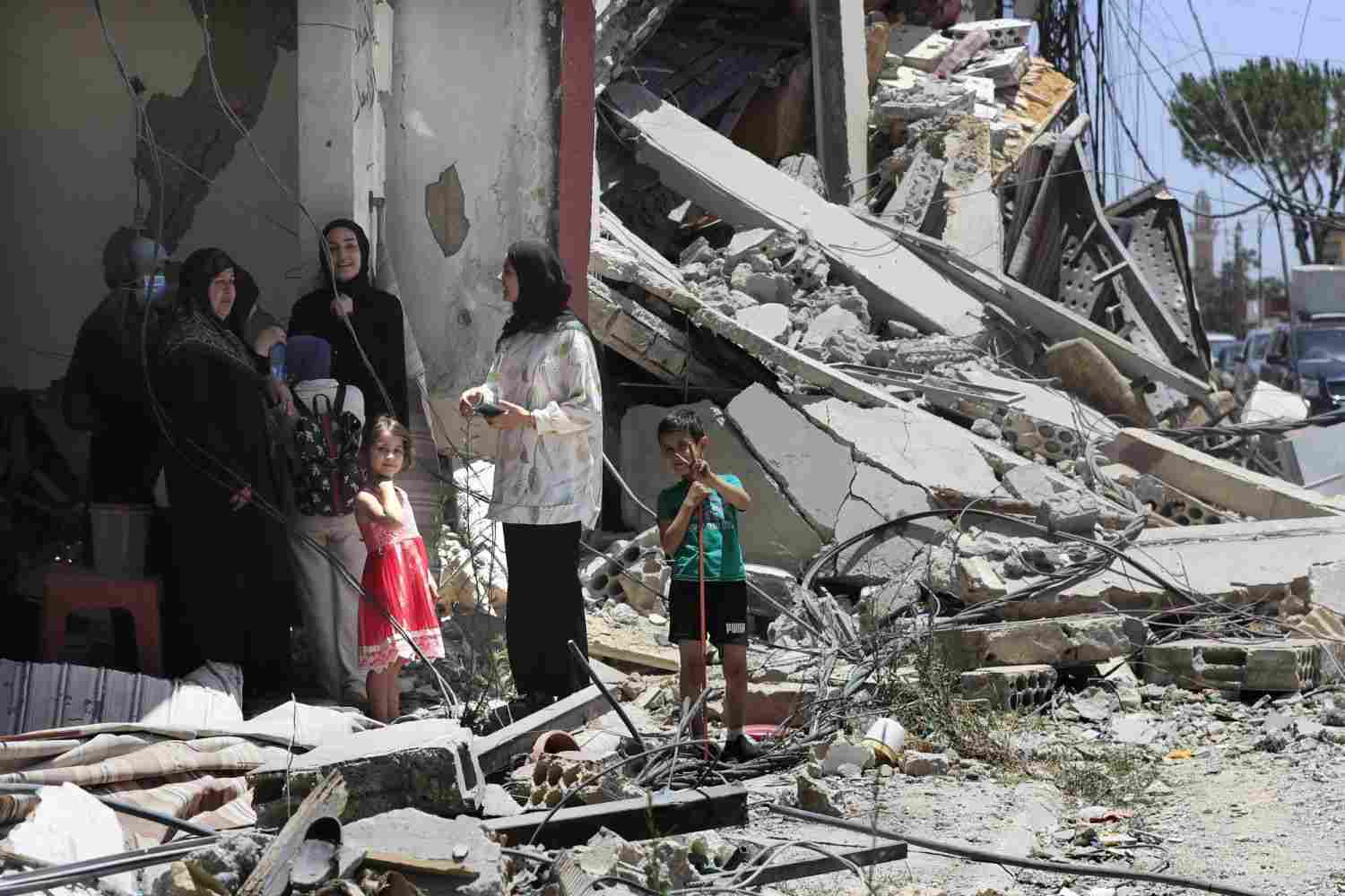 A Lebanese family stands next to a destroyed building