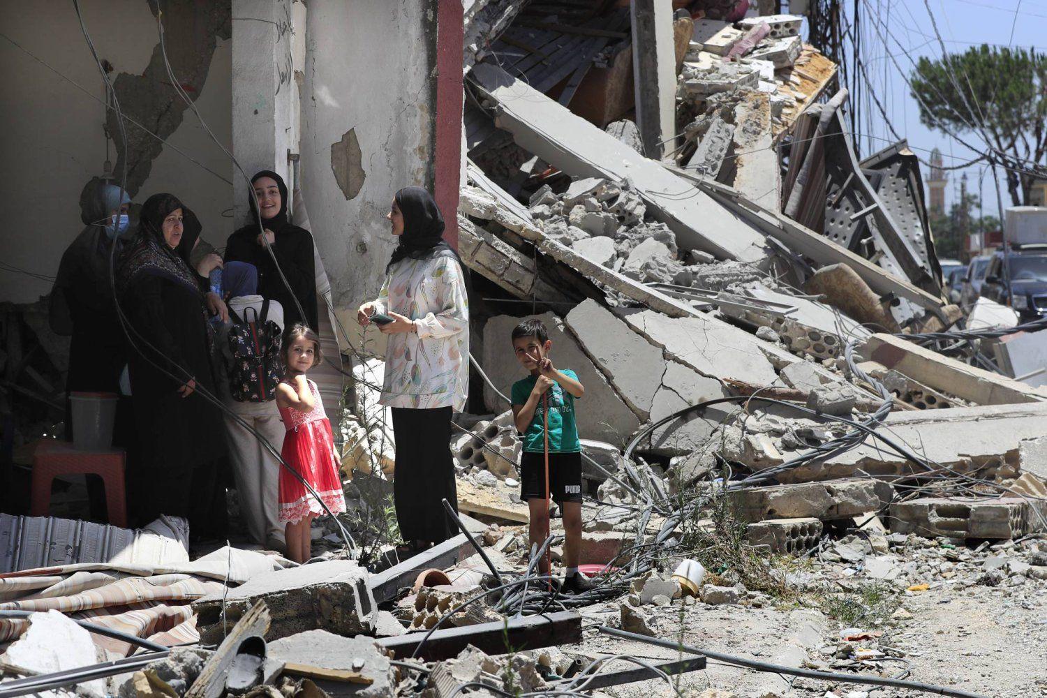 A Lebanese family stands next to a destroyed building A Lebanese family stands next to a destroyed building