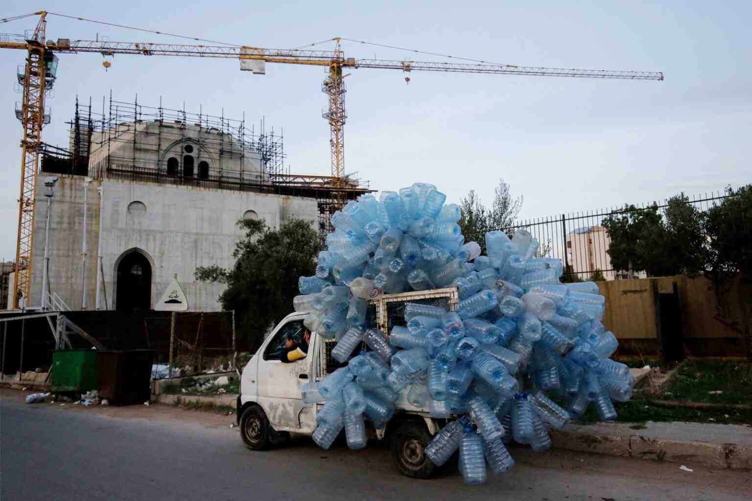 A van driver transports empty plastic containers for recycling in the northern Lebanese port city of Tripoli on December 10, 2024. (Photo by Ibrahim Chalhoub / AFP)