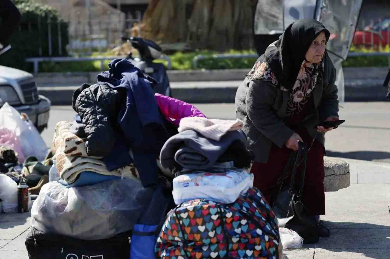 A woman sits on the ground beside her belongings on Beirut’s seaside corniche (EPA)