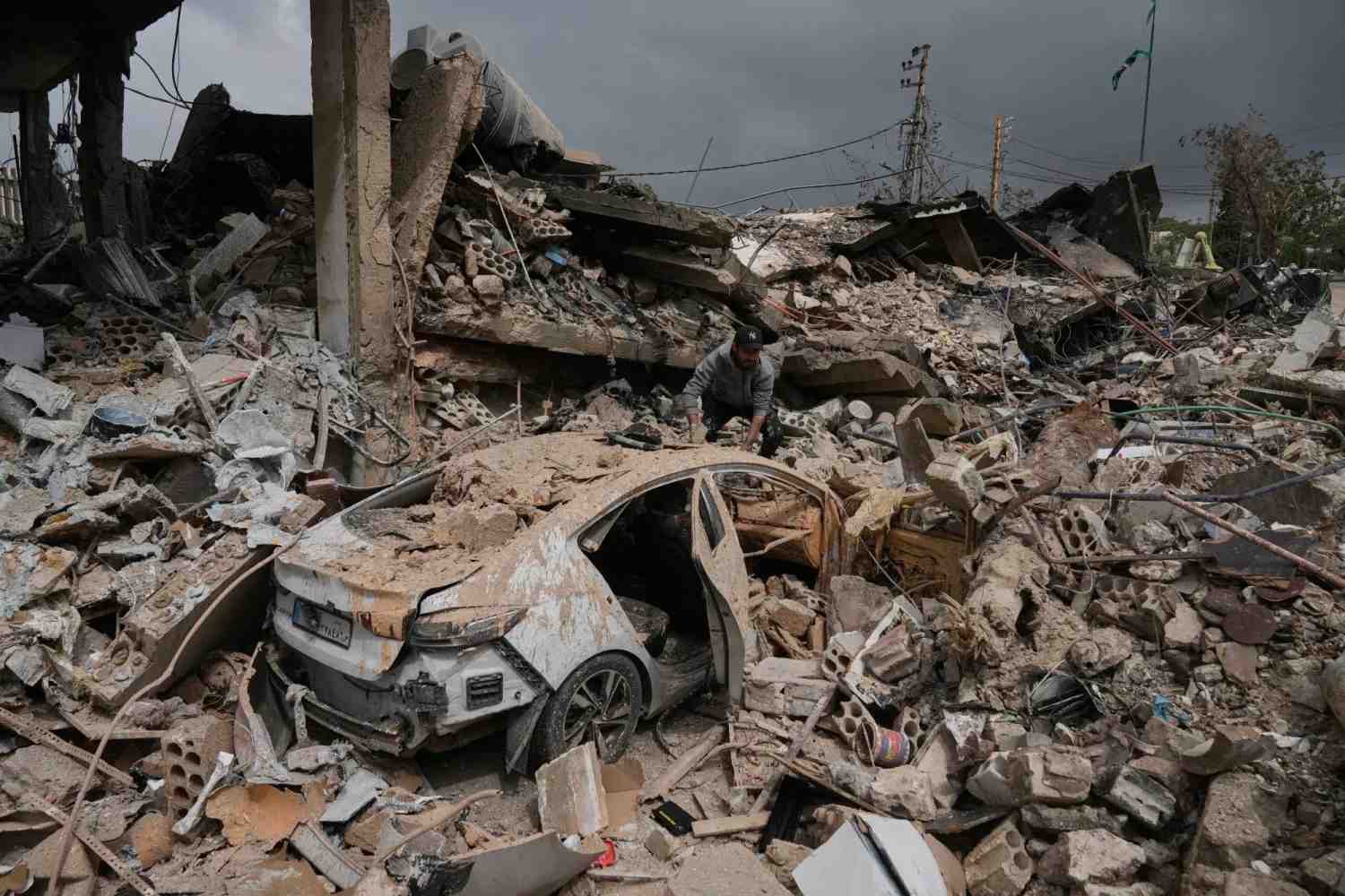 A man inspects his damaged car among the rubble of shops destroyed in previous Israeli airstrikes in the Hosh neighborhood of Tyre, southern Lebanon, April 19, 2026. (Image Credit: AP Photo/Bilal Hussein)